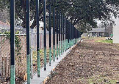 Black Metal Fence Posts Mounted into Concrete Footing